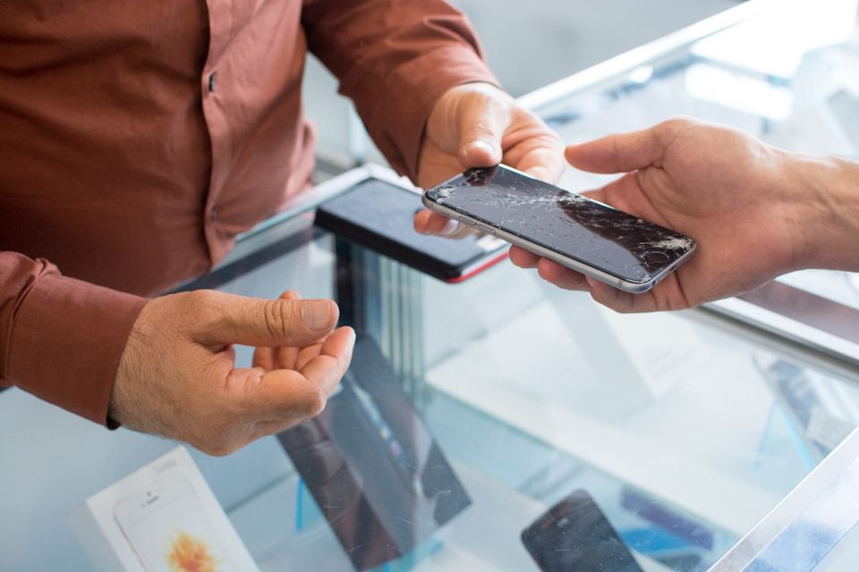 Klant overhandigt een smartphone aan een technicus aan de balie