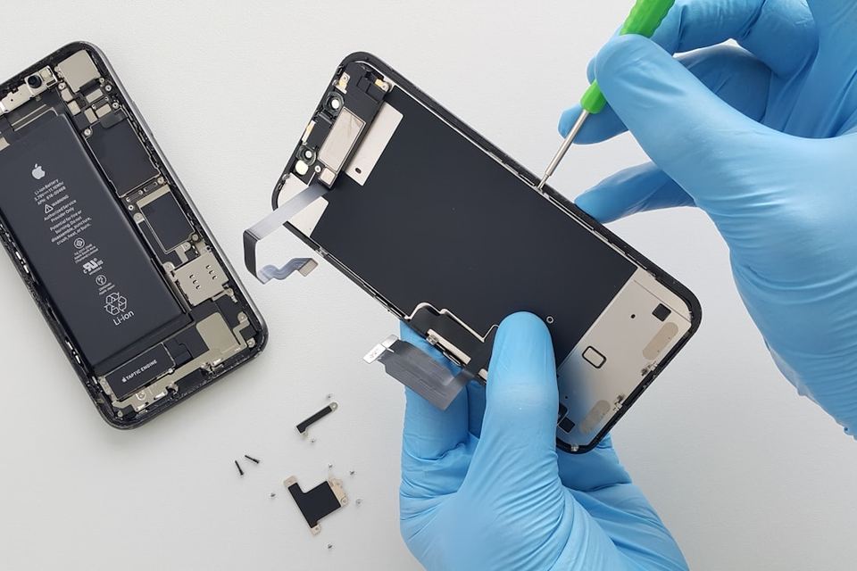 Technicus met handschoenen die een opengemaakte smartphone reinigt