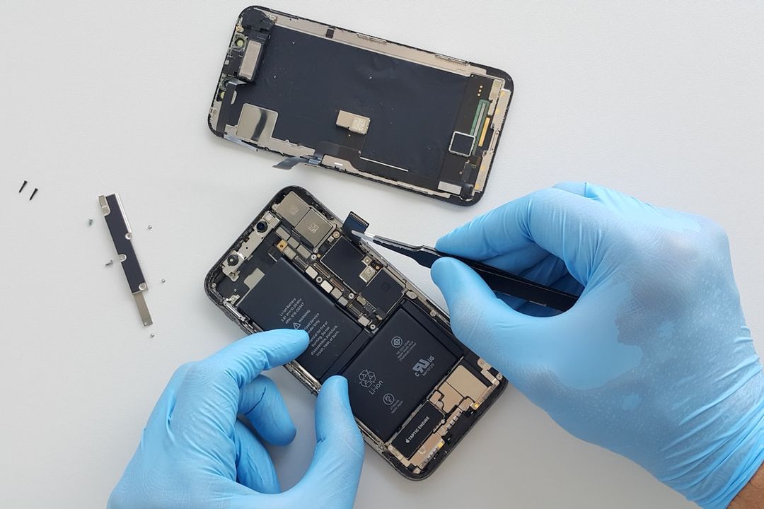 Technicus met handschoenen die een opengemaakte smartphone repareert